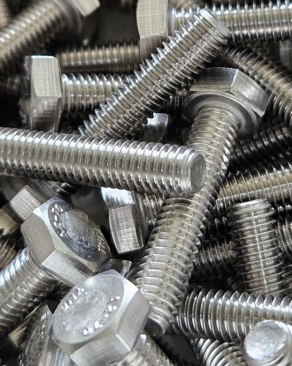 Close-up of a pile of stainless steel hex head bolts